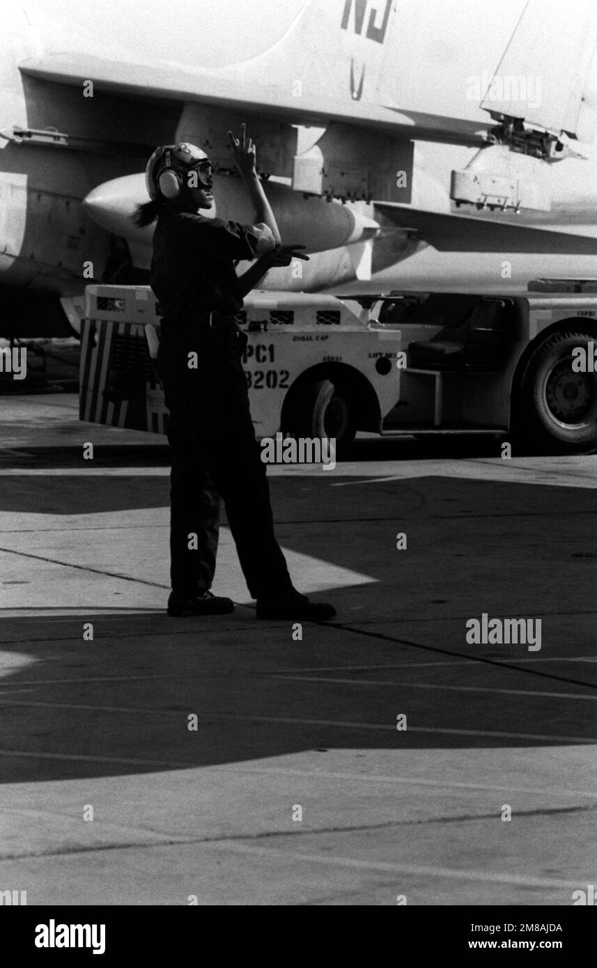 AIRMAN Ora Howard, plane captain, signals instructions to the pilot of