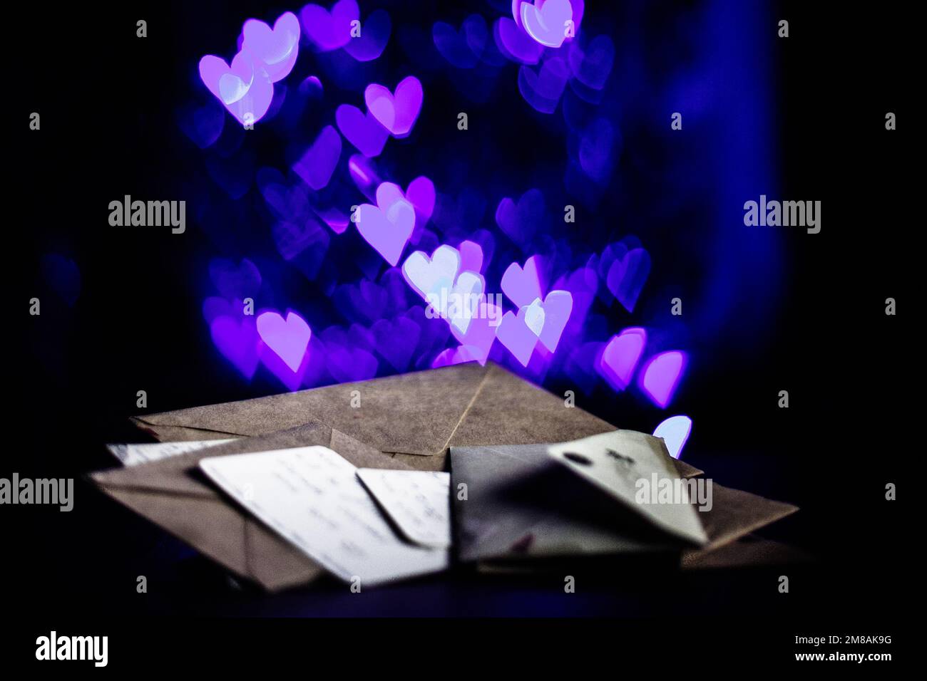 Valentines day letters, cards, glowing purple hearts in the dark Stock Photo