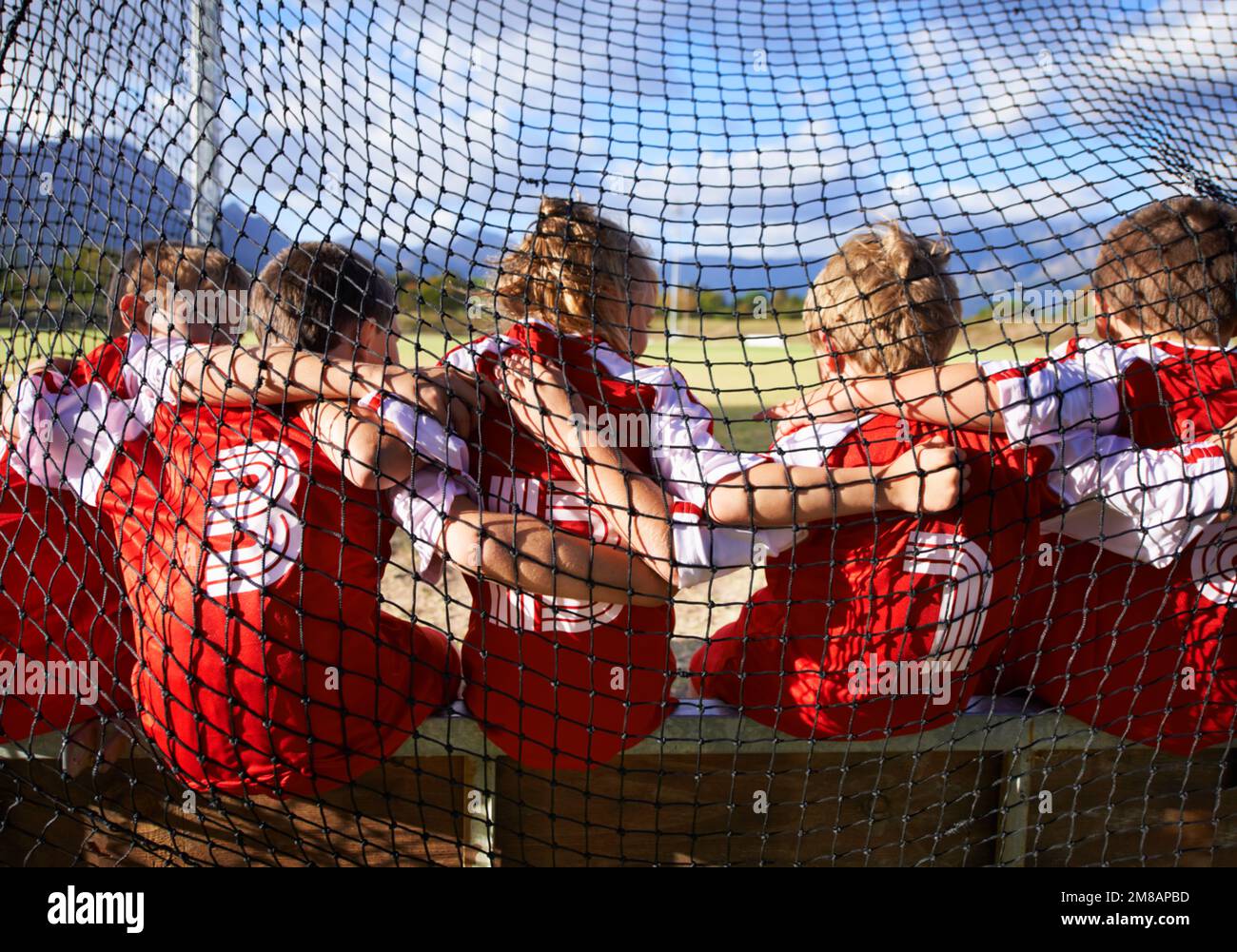 They stand together as a team. A team of soccer kids sitting inside the