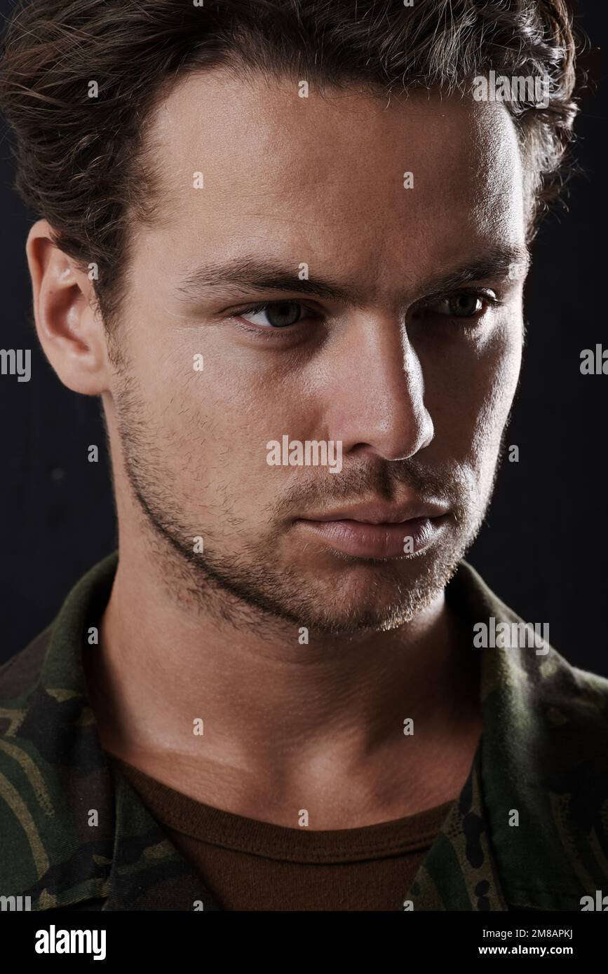 War changes a man. Cropped view of a man in fatigues looking serious against a black background. Stock Photo