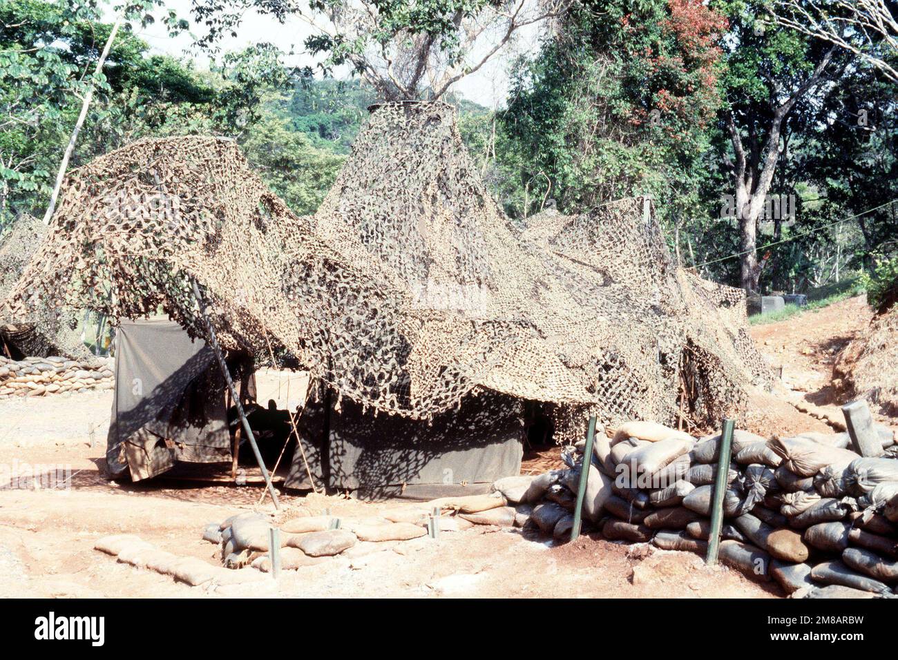 A camouflage net cover a command post tent in a fortified compound at a