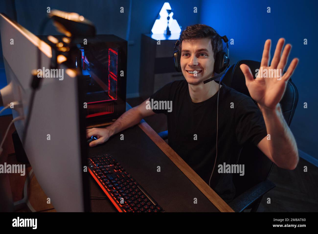 Professional cyber gamer having live stream, waving hand to followers and subscribers of his internet channel,