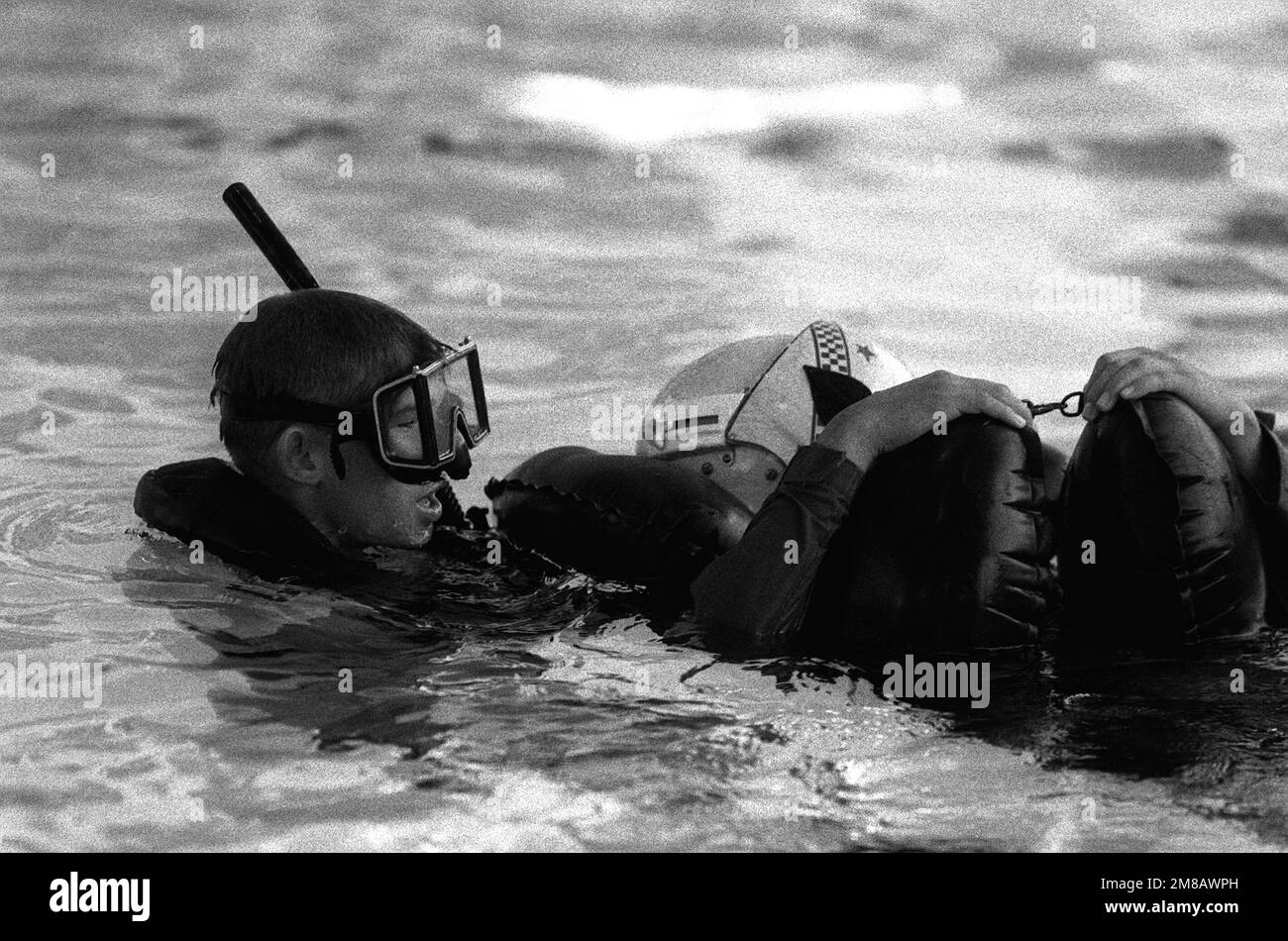 A student comes to the aid of a downed aviator during a simulated rescue, part of the twenty-day, intensive training course at the Navy Rescue Swimmer School. Exact Date Shot Unknown. Base: Naval Air Station, Pensacola State: Florida (FL) Country: United States Of America (USA) Stock Photo