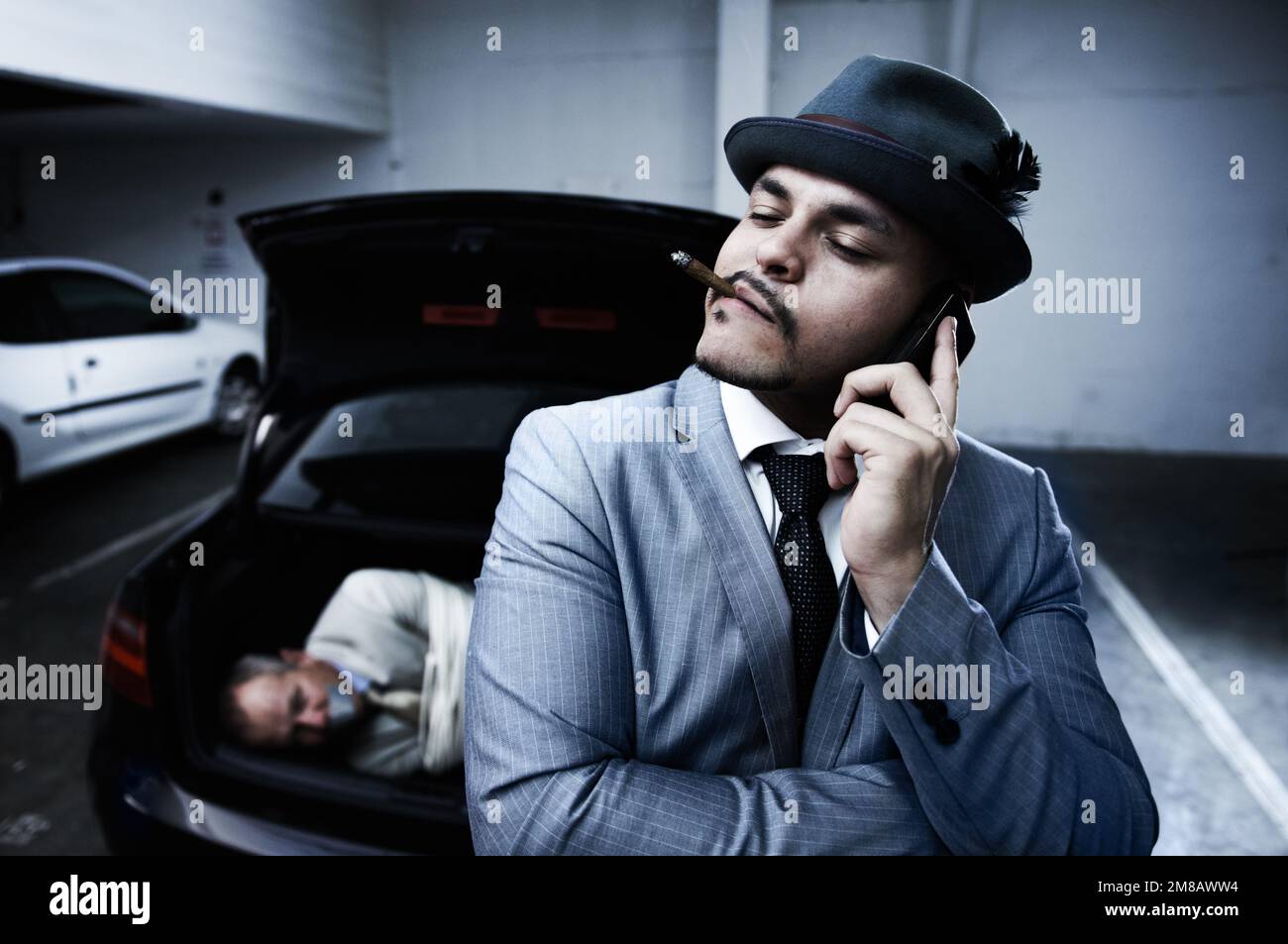 Arrogant and dangerous. An arrogant mobster smoking a cigar and informing his boss that the abduction was successful. Stock Photo