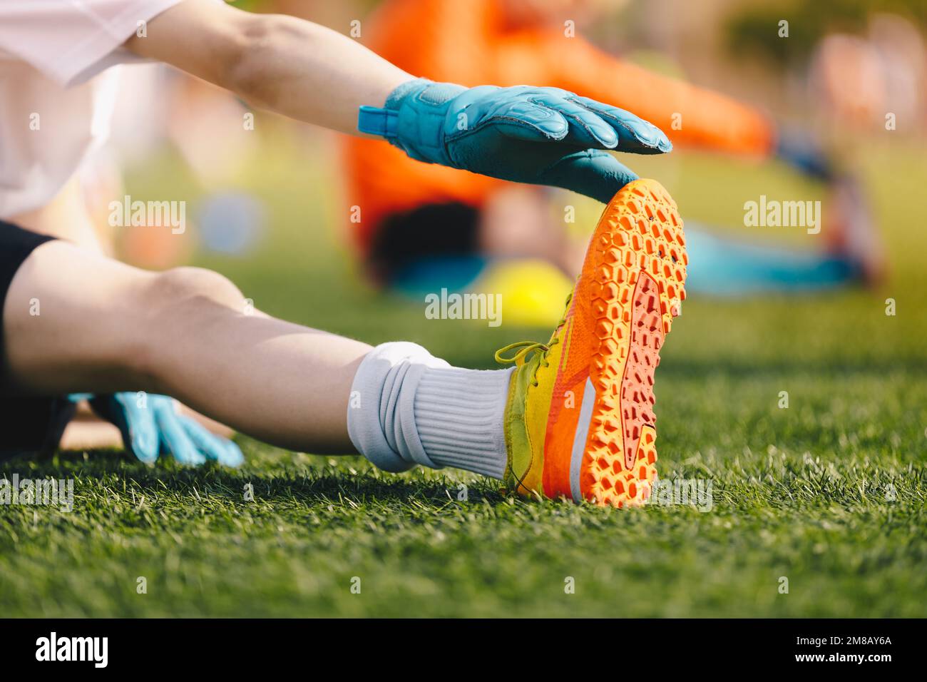 Stretches for young soccer goalies. Schoolboy at training session