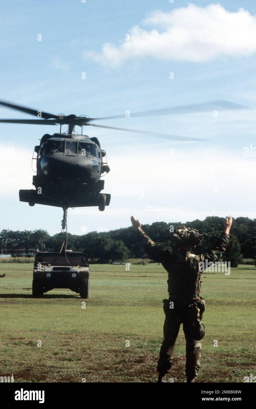 A soldier signals the pilot of a UH-60 Black Hawk helicopter to begin ...
