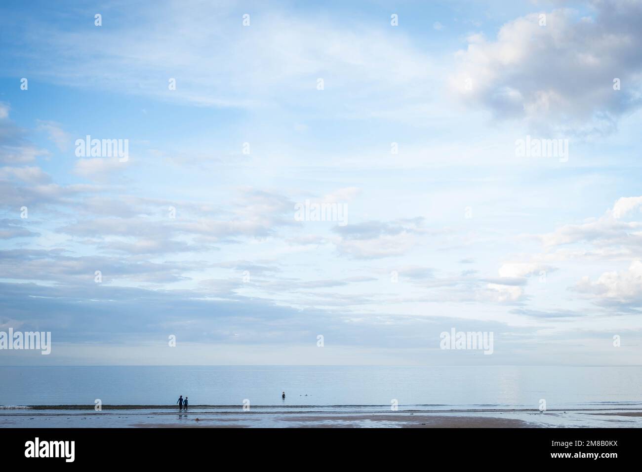 Silhouetted couple walking in the sea at dusk in Northumberland, uk Stock Photo