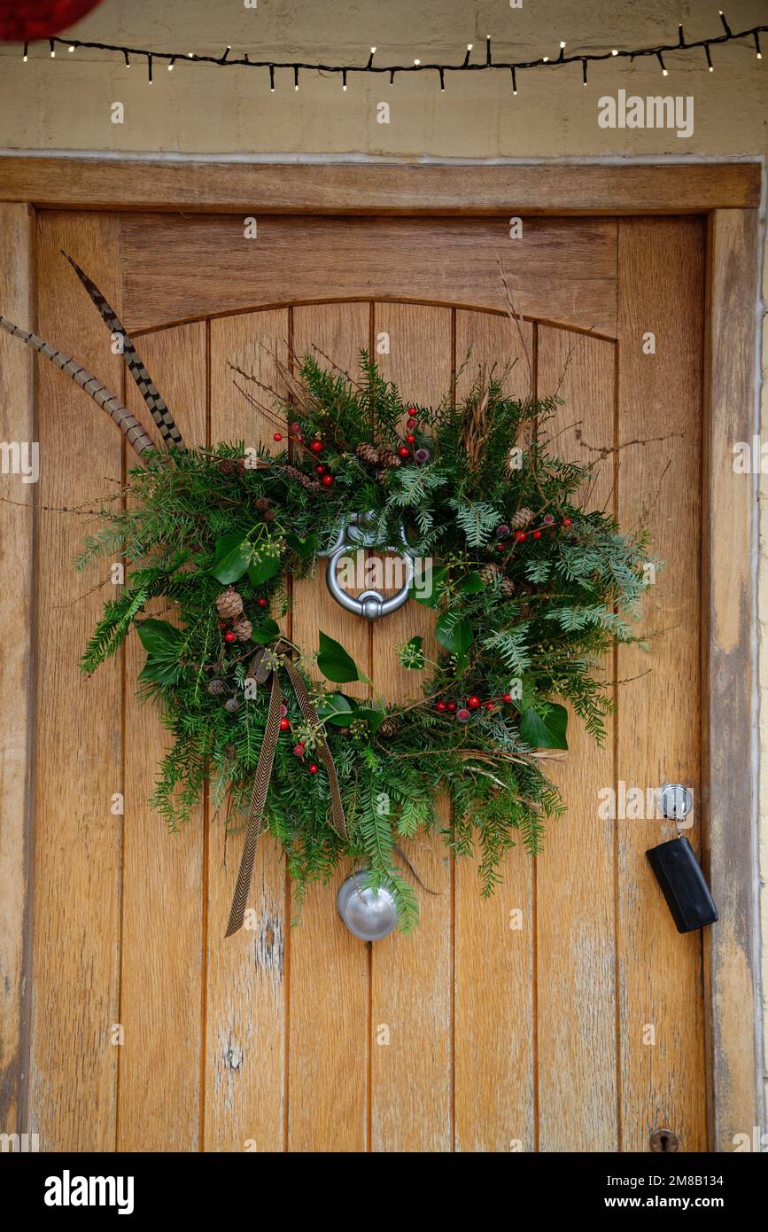 A Christmas wreath displayed on a wooden front door. Stock Photo