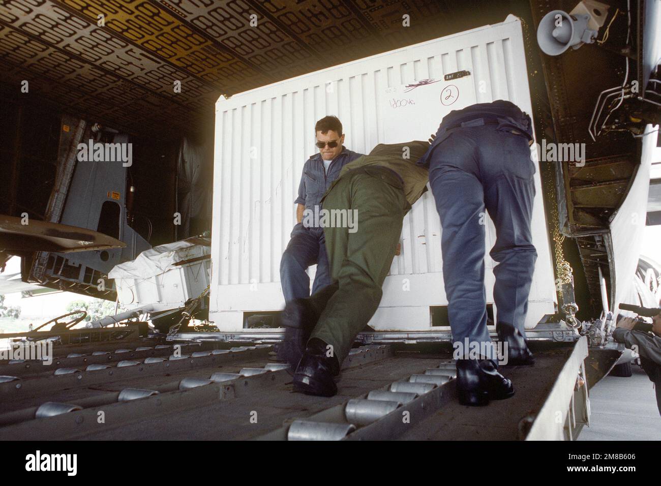 U.S. and Australian personnel push a container of equipment and ...