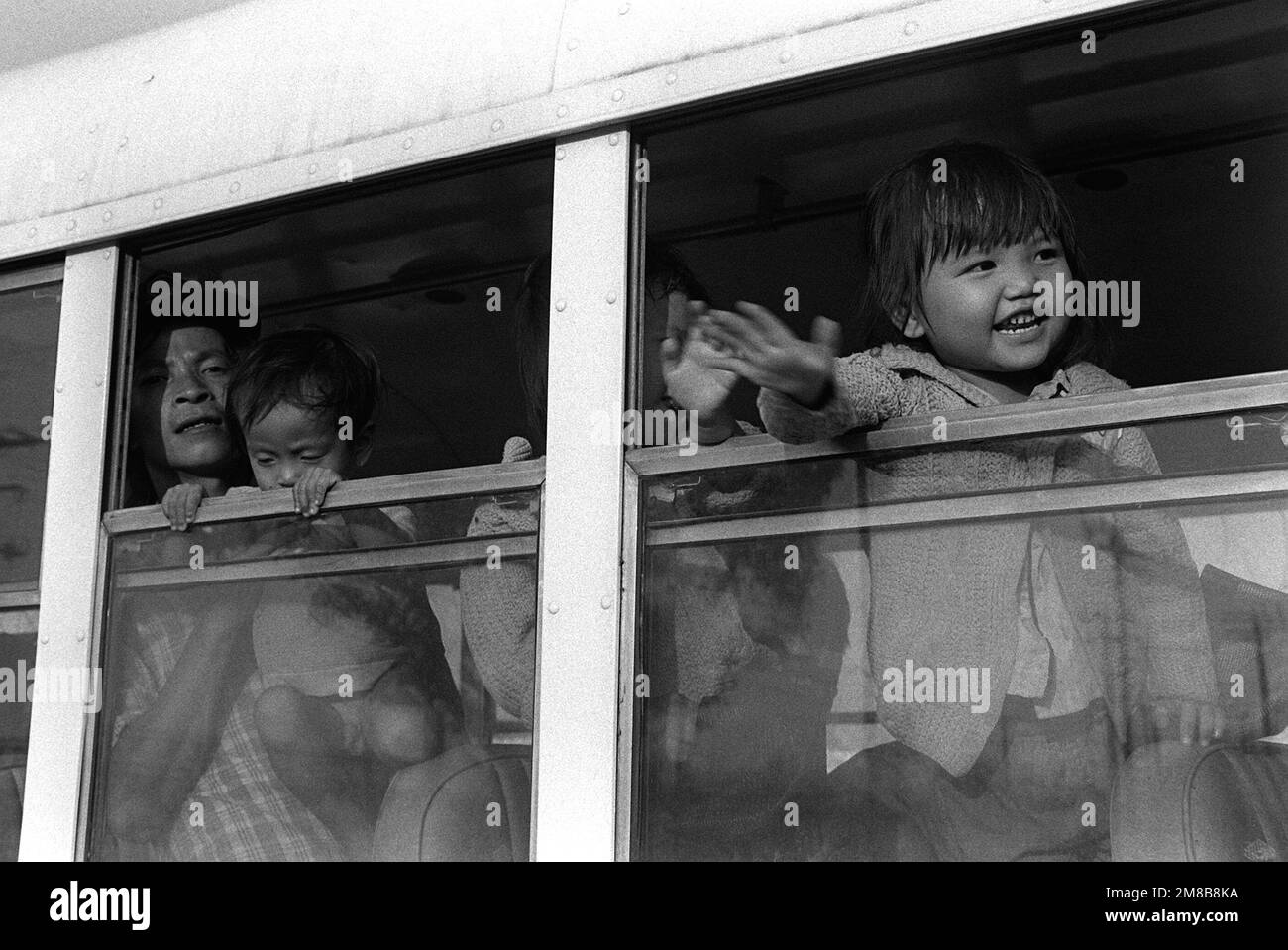 A Vietnamese refugee child smiles happily as she waves from a bus window. A total of 109 refugees are being transported to temporary quarters after arriving at Naval Base, Subic Bay aboard the petroleum tanker OVERSEAS VIVIAN (T-AOT-2006). The commercial tanker, which is operating under a charter with the Navy's Military Sealift Command, is transporting 109 Vietnamese refugees to Naval Base, Subic Bay, following their recovery from a disabled boat in the South China Sea on April 20th. Exact Date Shot Unknown. Country: Philippines (PHL) Stock Photo