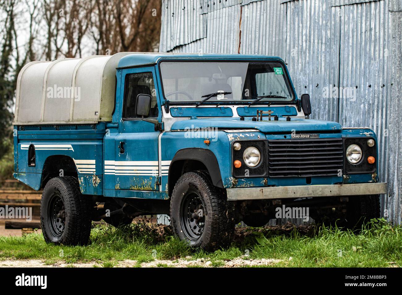 Old classic vintage pick-up Land Rover next to metal shed Stock Photo