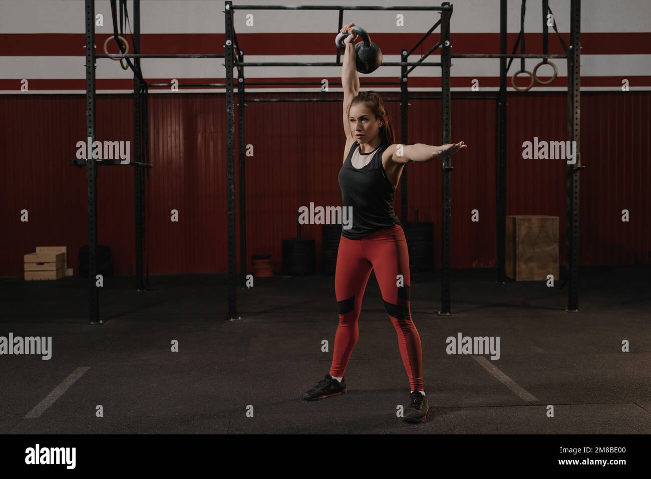 Young crossfit woman lifting a heavy weight kettlebell at gym