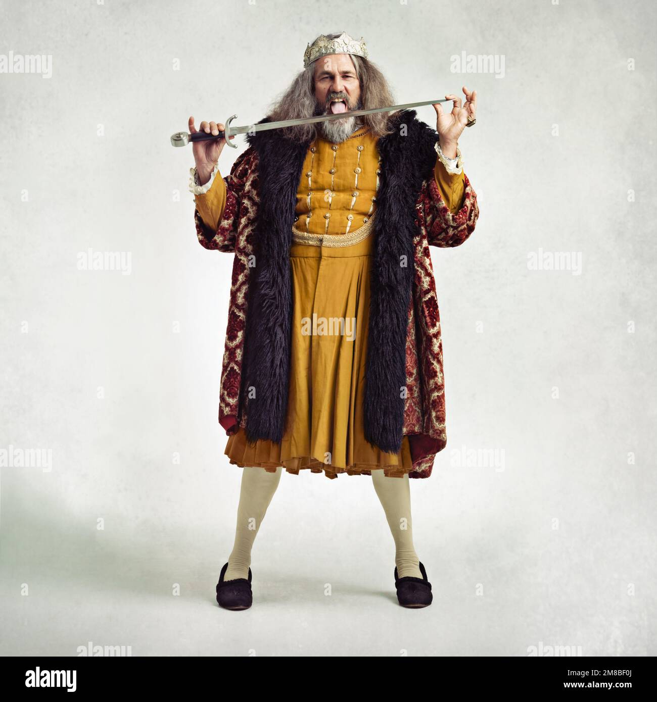 King, portrait and man lick sword in studio isolated on gray background