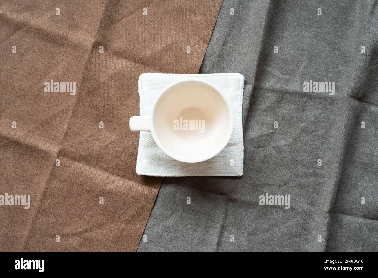 White empty coffee cup on brown and gray fabric background. top view Stock Photo