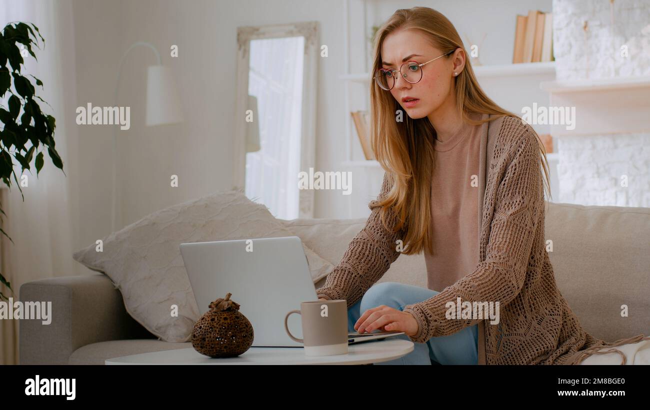 Caucasian shocked girl in glasses feel shock reading bad news woman lost with laptop worry about loosing online with computer terrible information Stock Photo