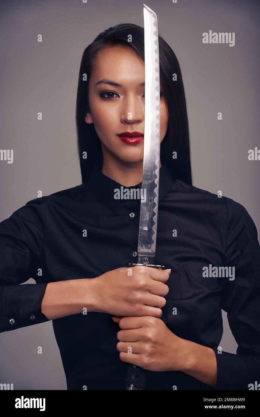 Portrait, ninja and sword with warrior woman in studio on a gray background for martial arts or combat. Training, fantasy and weapon with an asian Stock Photo