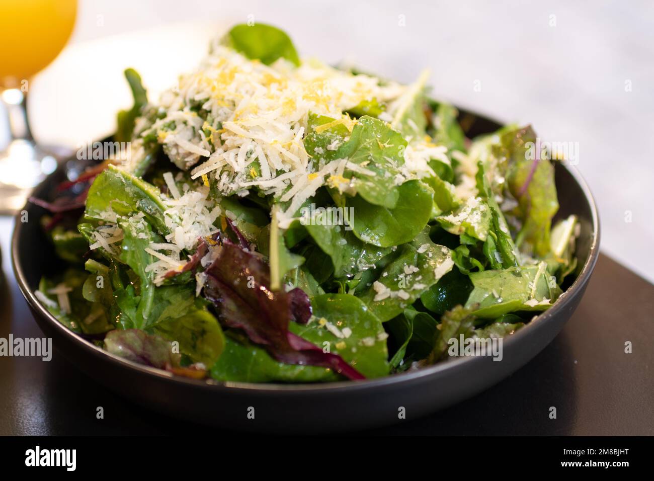 Fresh green salad topped with grated parmesan cheese and grated lemon