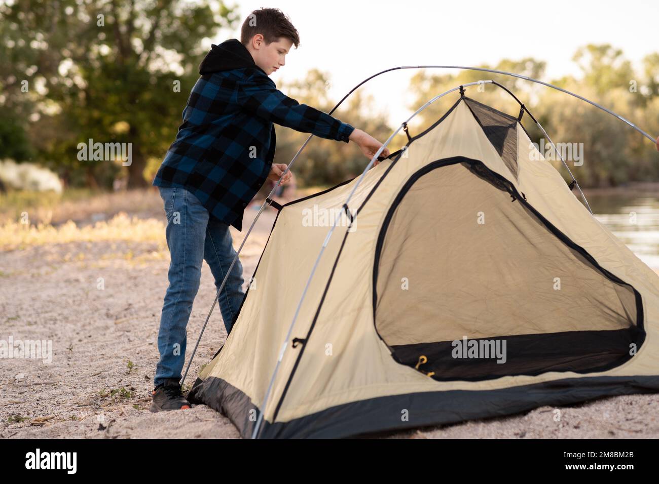 Camping people outdoor lifestyle tourists, summer river. boy installing tent. Natural children education Stock Photo