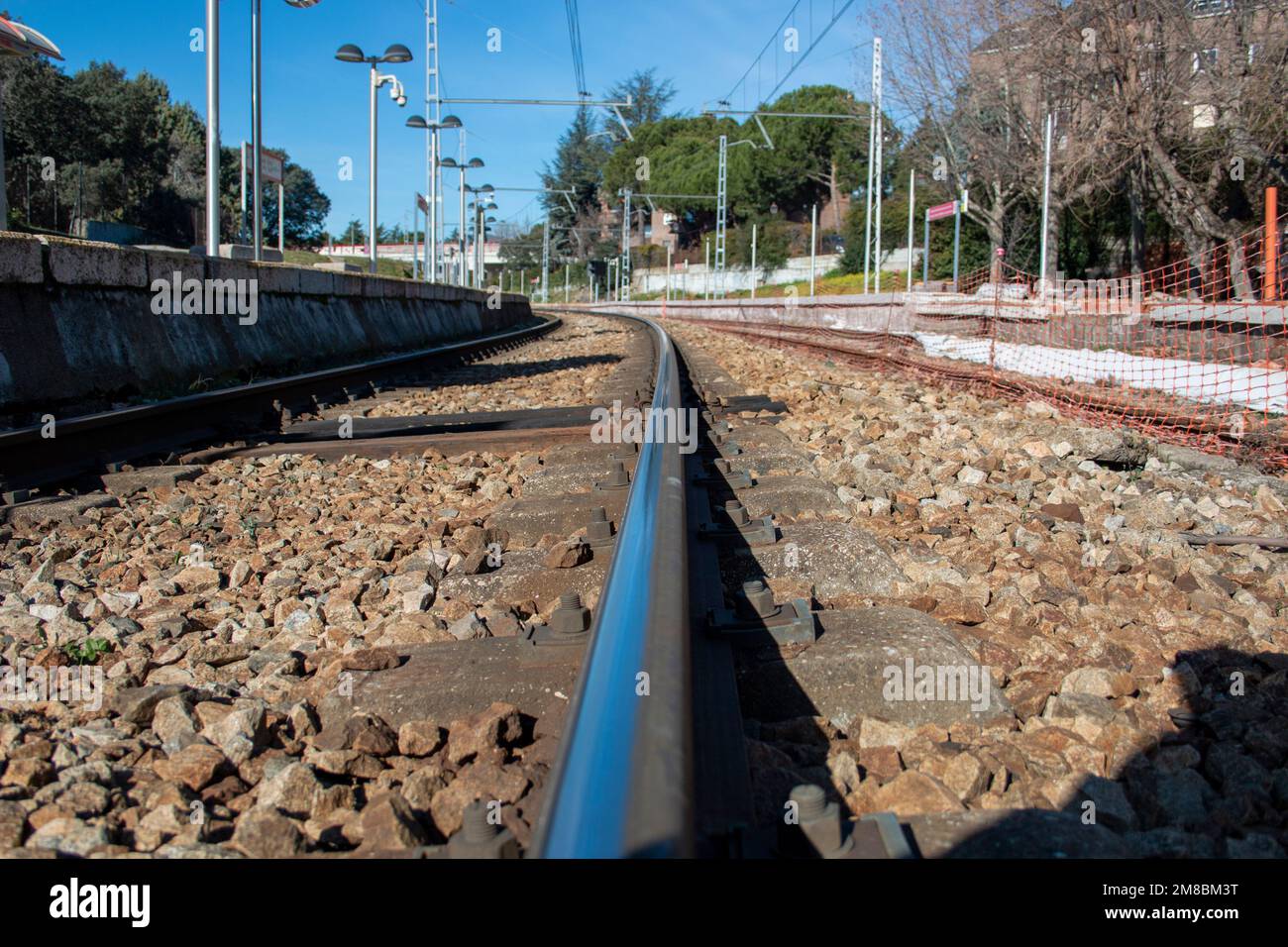 Train track rail in a very close plane on the station platform where metal, stones or power lines can be seen Stock Photo