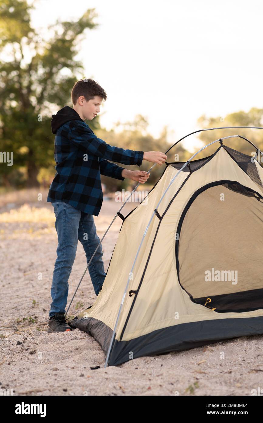 Cute boy teen son assembling tent. Natural education of children. lifestyle tourists. Copy space Stock Photo