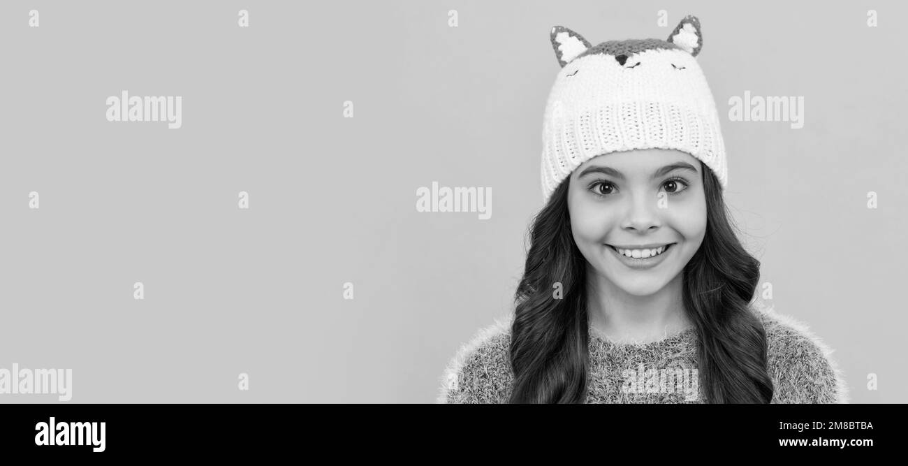 happy child in sweater and hat on yellow background, winter. Child face, horizontal poster, teenager girl isolated portrait, banner with copy space. Stock Photo