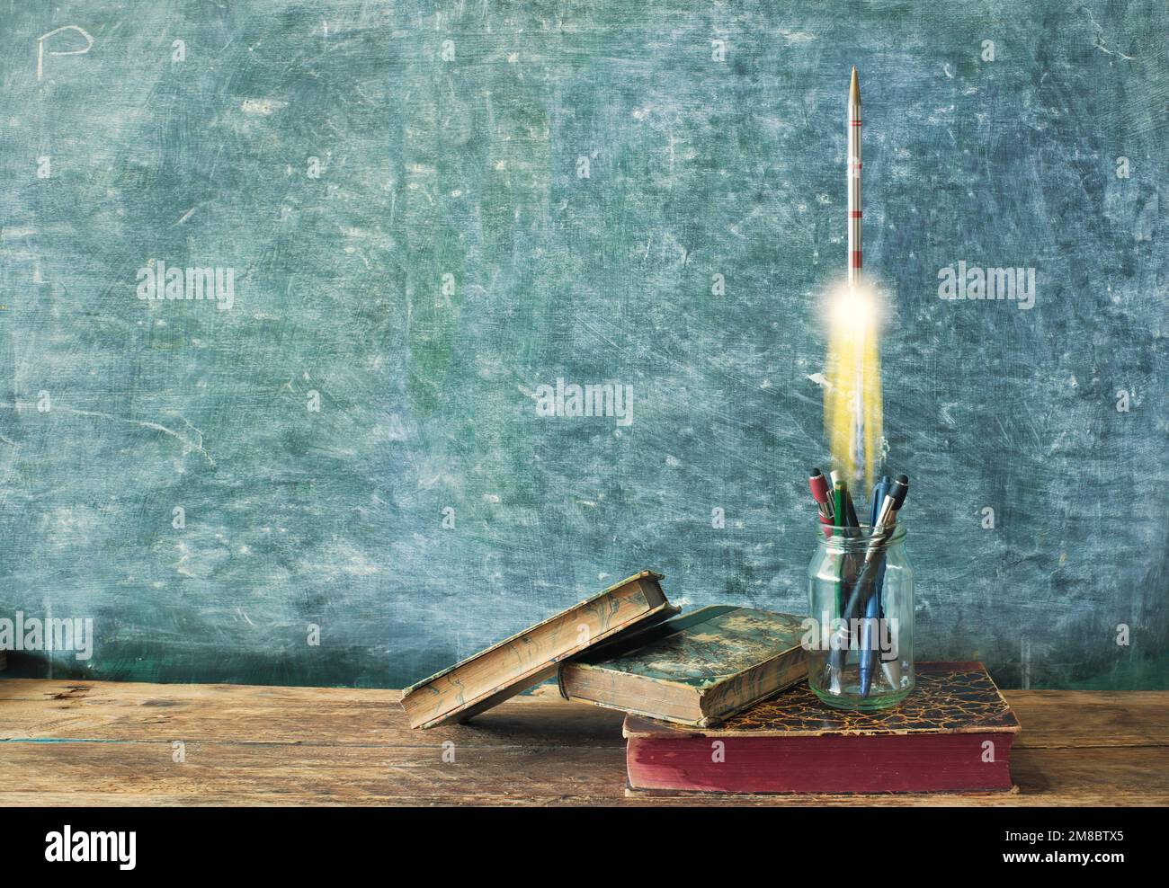 inspiration,education, knowledge and idea concept,books, supplies and a rocket launching in front of a blackboard, free copy space Stock Photo