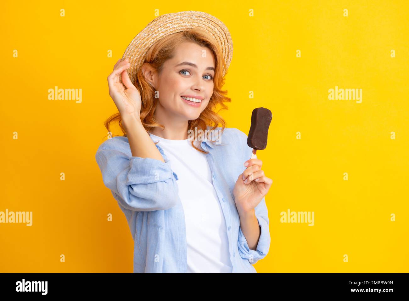 Young woman eat ice creams with chocolate glaze on yellow background