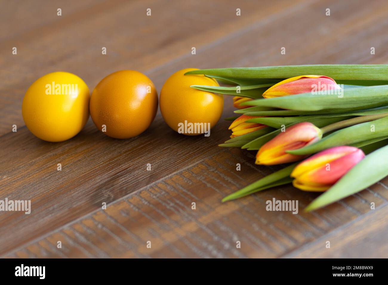 Golden Easter eggs with tulips on a wooden background Stock Photo - Alamy