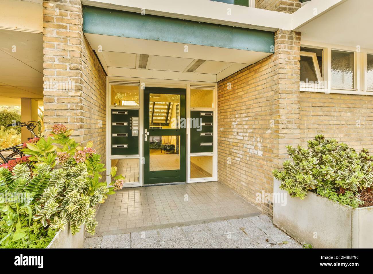 the front entrance to an apartment with green doors and plants in pots on either side of the entryway, Stock Photo