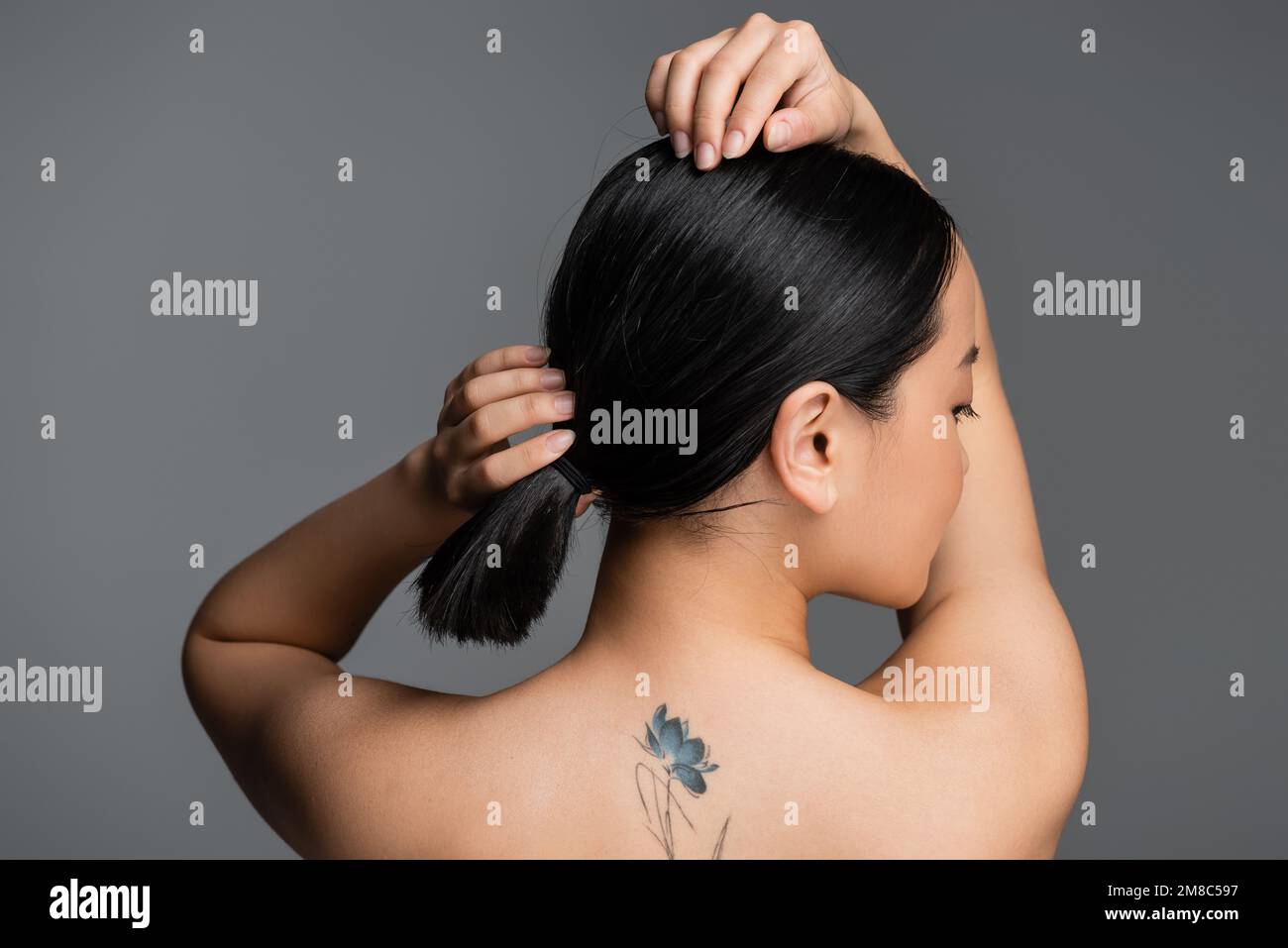 Woman with tattooed shoulders adjusting bra straps stock photo