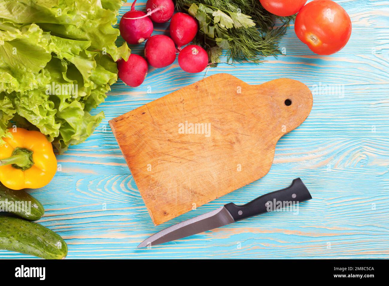 https://c8.alamy.com/comp/2M8C5CA/fresh-vegetables-and-cutting-board-with-knife-on-blue-wooden-background-top-view-2M8C5CA.jpg