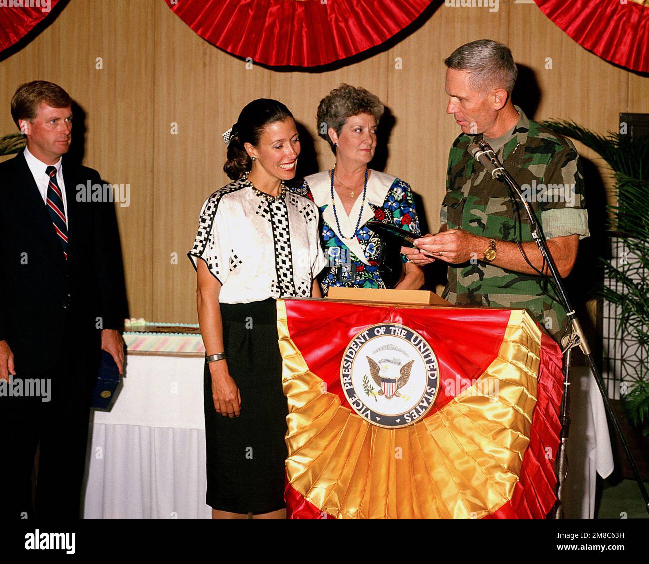 Vice President Dan Quayle, left, looks on as his wife, Marilyn, second from left, accepts a gift from Lieutenant General Norman H. Smith, Deputy CHIEF of STAFF for Manpower and Reserve Affairs, US Marine Corps, during a reception at the officers club. Base: Marine Corps Base, Camp Hansen State: Okinawa Country: Japan (JPN) Stock Photo