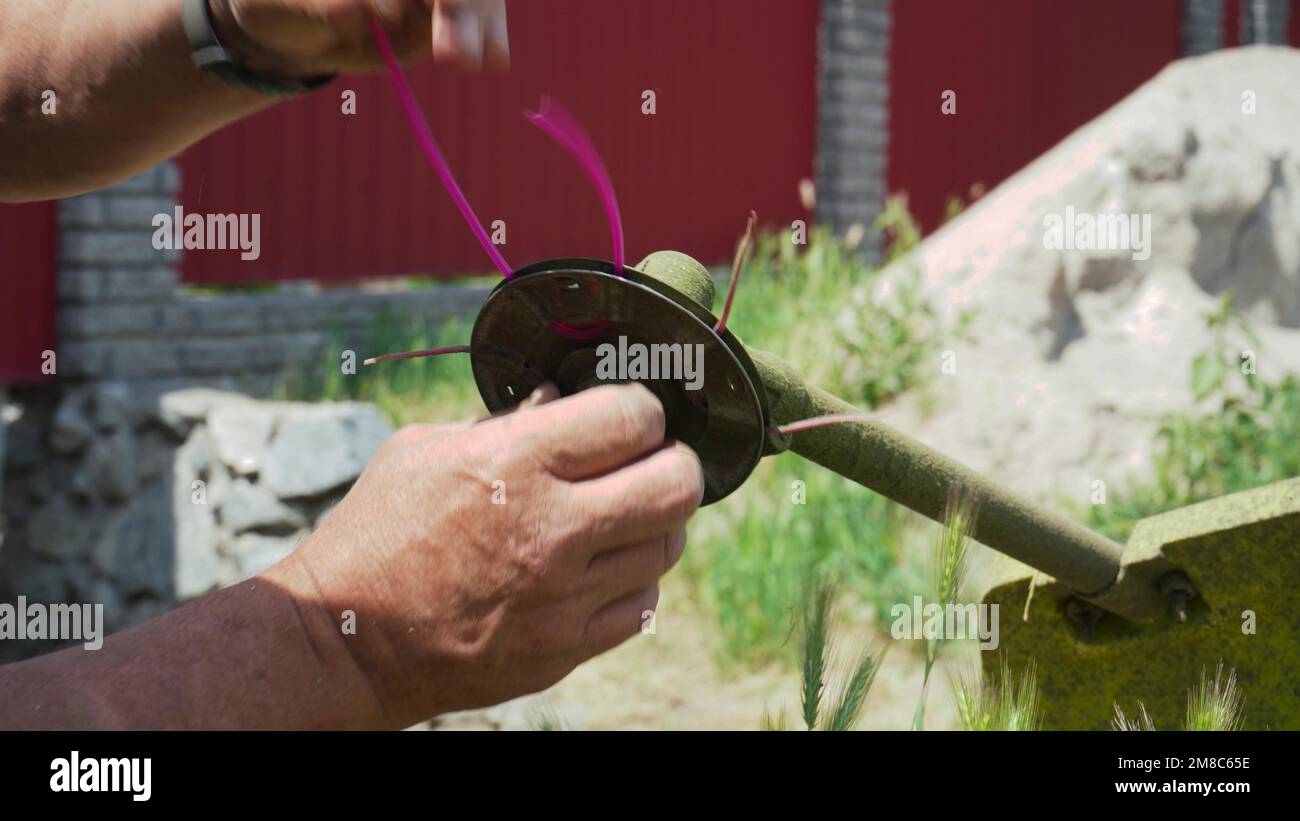 Closeup of a man's hand taking apart a lawn mower to replace parts