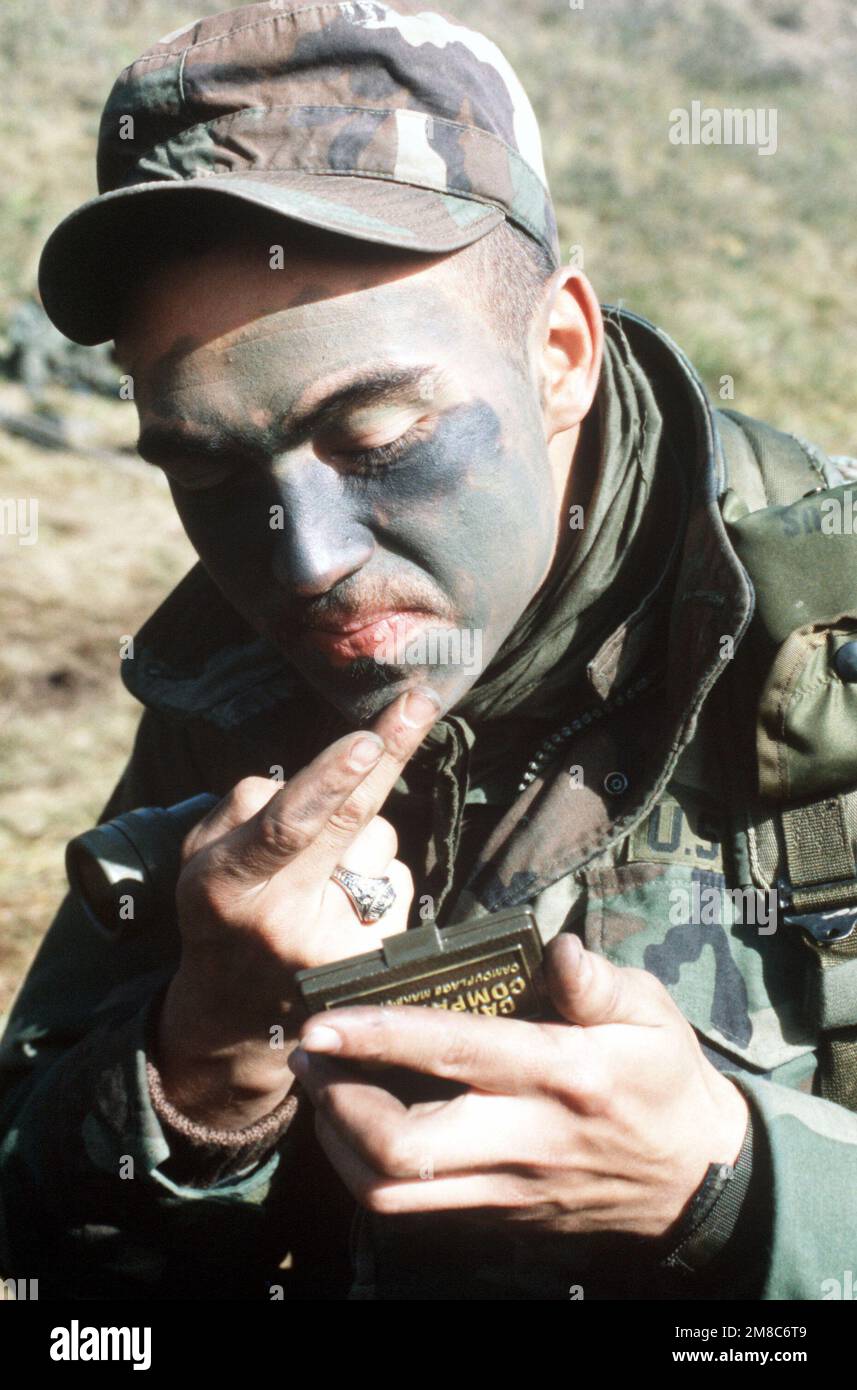 A member of Co. C, 2nd Bn., 297th Infantry Group (Scout), Alaska National Guard, applies camouflage paint to his face while waiting for an aggressor attack during Kernal Potlatch '89. Subject Operation/Series: KERNAL POTLATCH '89 Base: Amchitka Island State: Alaska (AK) Country: United States Of America (USA) Stock Photo