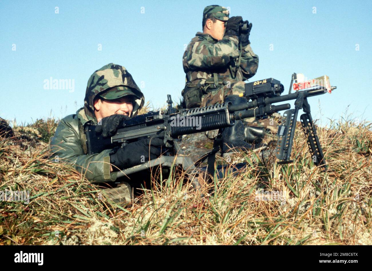 A machine gun team from Co. C, 2nd Bn., 297th Infantry Group (Scout), Alaska National Guard, waits for the approach of aggressor forces during exercise Kernal Potlatch '89. The soldier's M-60 machine gun is equipped with multiple integrated laser engagement system (MILES) units. Subject Operation/Series: KERNAL POTLATCH '89 Base: Amchitka Island State: Alaska (AK) Country: United States Of America (USA) Stock Photo