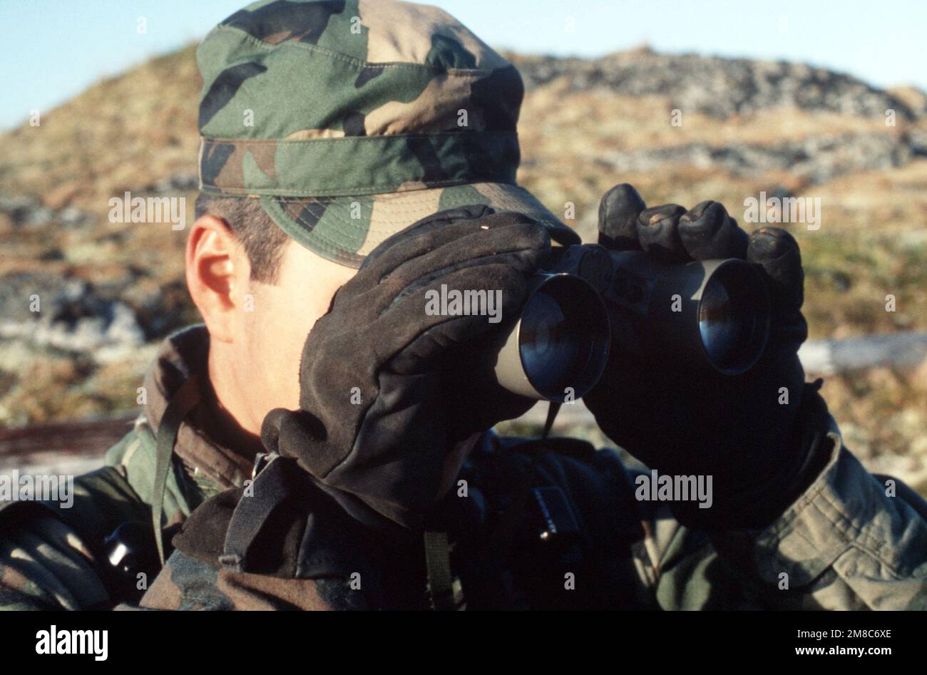 PFC Palmer Olrun, a member of Co. C, 2nd Bn., 297th Infantry Group (Scout), Alaska National Guard, scans the area for aggressor forces during exercise Kernal Potlatch '89. Subject Operation/Series: KERNAL POTLATCH '89 Base: Amchitka Island State: Alaska (AK) Country: United States Of America (USA) Stock Photo