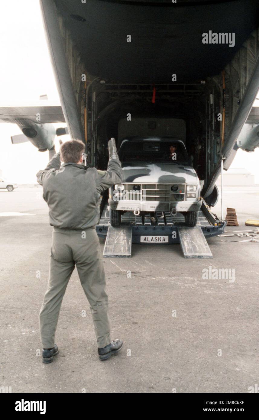 An airman guides an M-1008 tactical cargo truck as it is driven off of an Air Force C-130 Hercules aircraft at the start of exercise Kernal Potlatch '89. The vehicle is assigned to the 207th Infantry Group (Scout), Alaska National Guard. Subject Operation/Series: KERNAL POTLATCH '89 Base: Amchitka Island State: Alaska (AK) Country: United States Of America (USA) Stock Photo