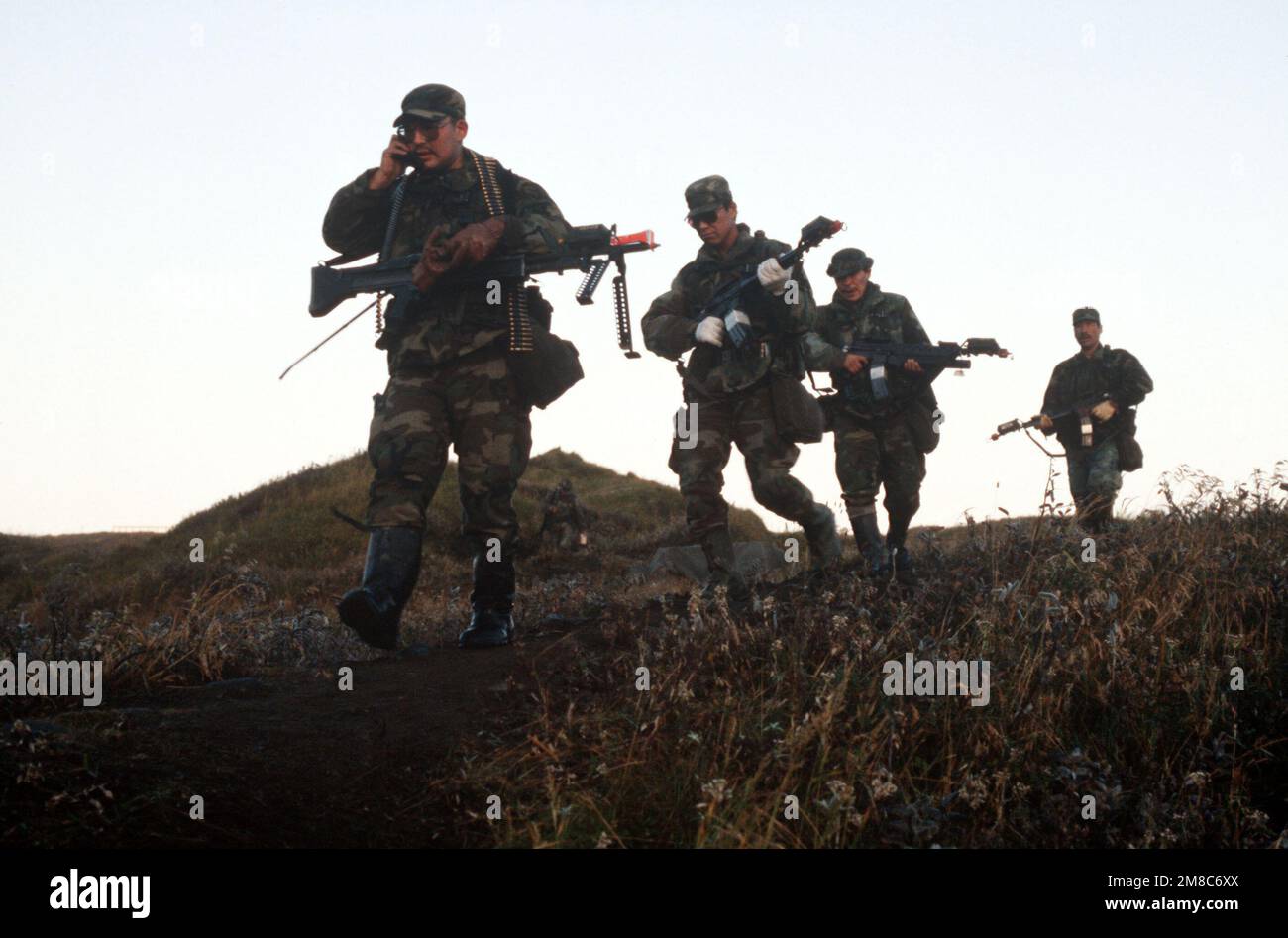 Four members of Co. C, 2nd Bn., 297th Infantry Group (Scout), Alaska National Guard, set out on an early morning patrol during exercise Kernal Potlatch '89. Their weapons are equipped with multiple integrated laser engagement system (MILES) units. Subject Operation/Series: KERNAL POTLATCH '89 Base: Amchitka Island State: Alaska (AK) Country: United States Of America (USA) Stock Photo