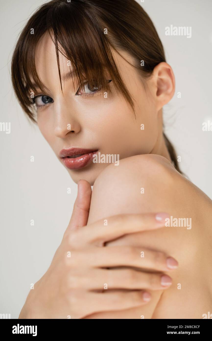 portrait of young woman with bangs looking at camera isolated on grey,stock image Stock Photo