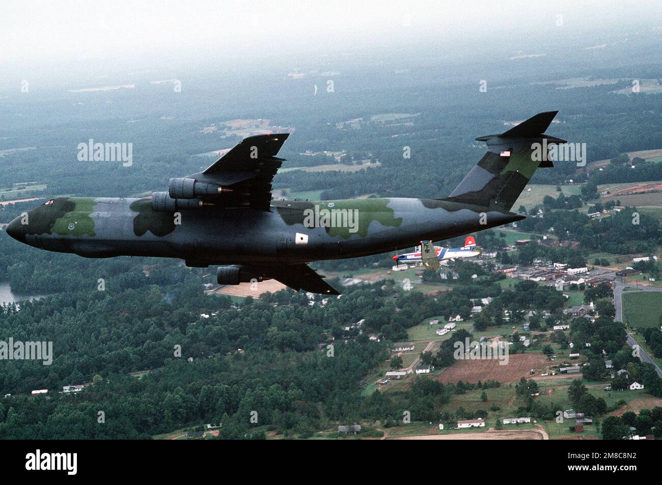 A Pilatus PC9 aircraft flies near the tail of a C5A Galaxy aircraft