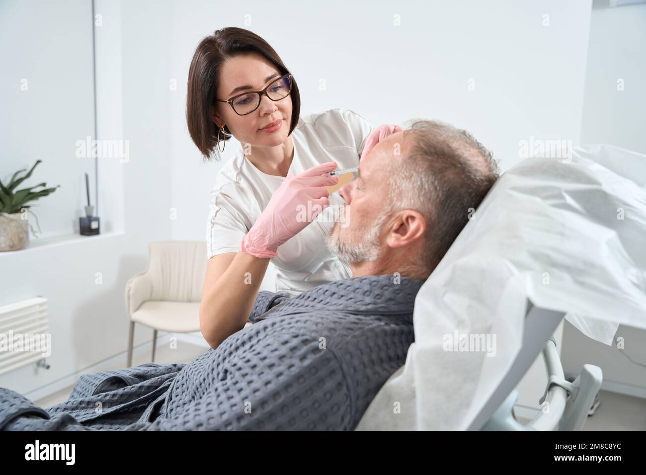 Doctor uses modern fillers for rejuvenating course for adult patient Stock Photo
