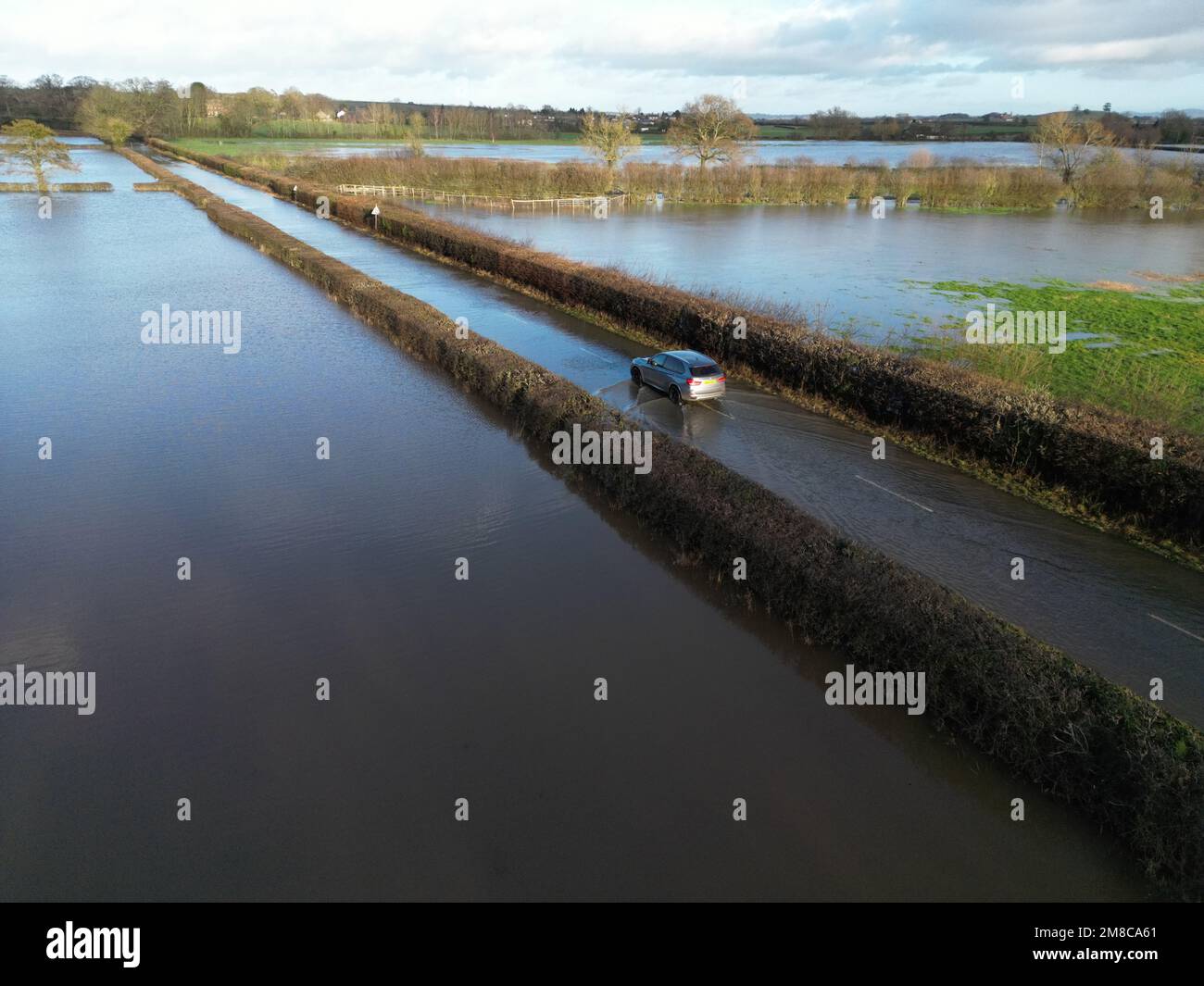 Sutton St Nicholas, Herefordshire, UK – Friday 13th January 2023 – UK Weather – Aerial view of vehicles driving through floodwater from the nearby River Lugg on a rural road between Sutton St Nicholas and Hereford. After days of rainfall local rivers such as the River Lugg, River Teme and River Wye are all at very high levels. More rain forecast. Photo Steven May / Alamy Live News Stock Photo