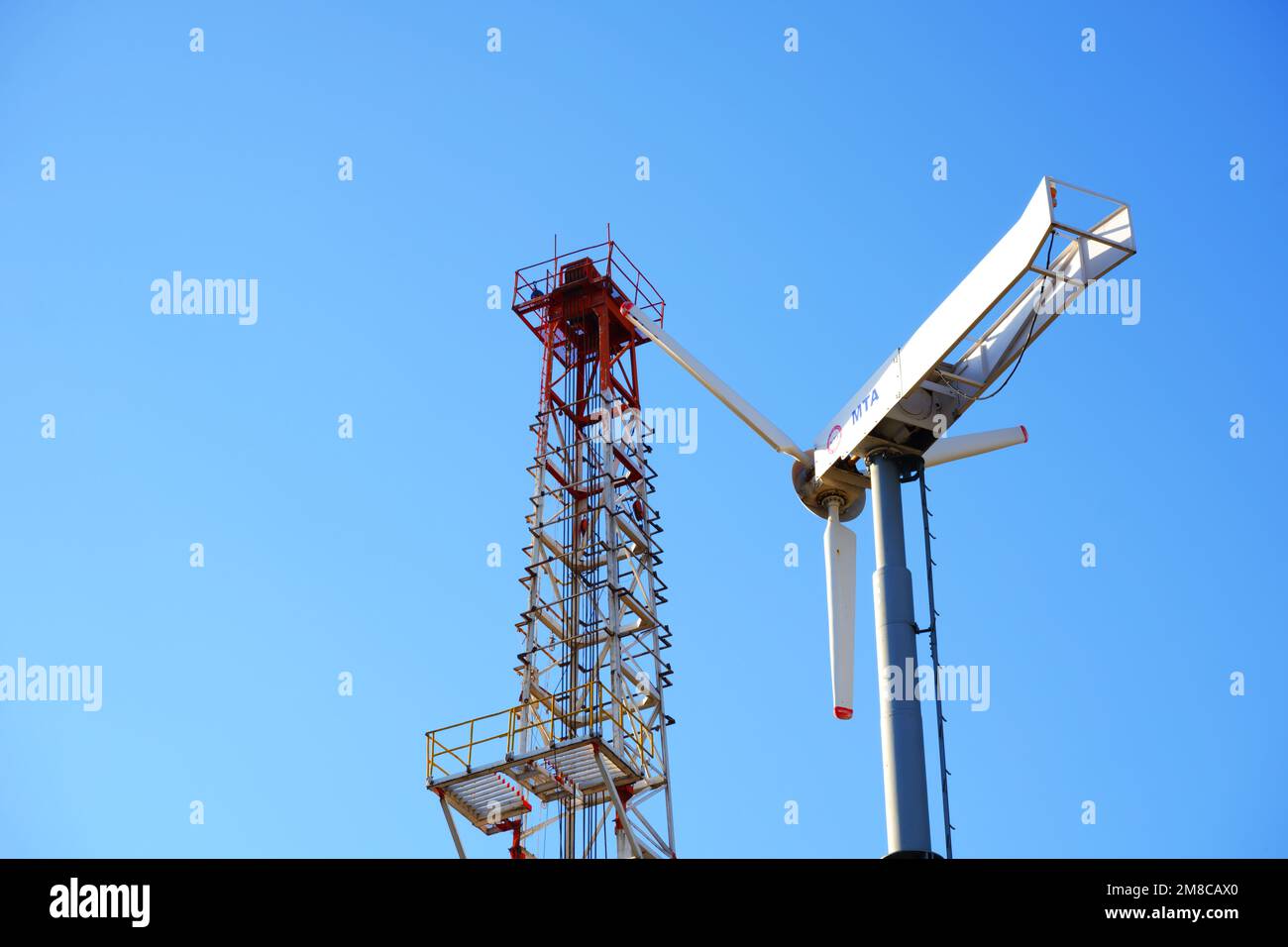 Wind turbine and drilling tower with blue sky at the background Stock Photo