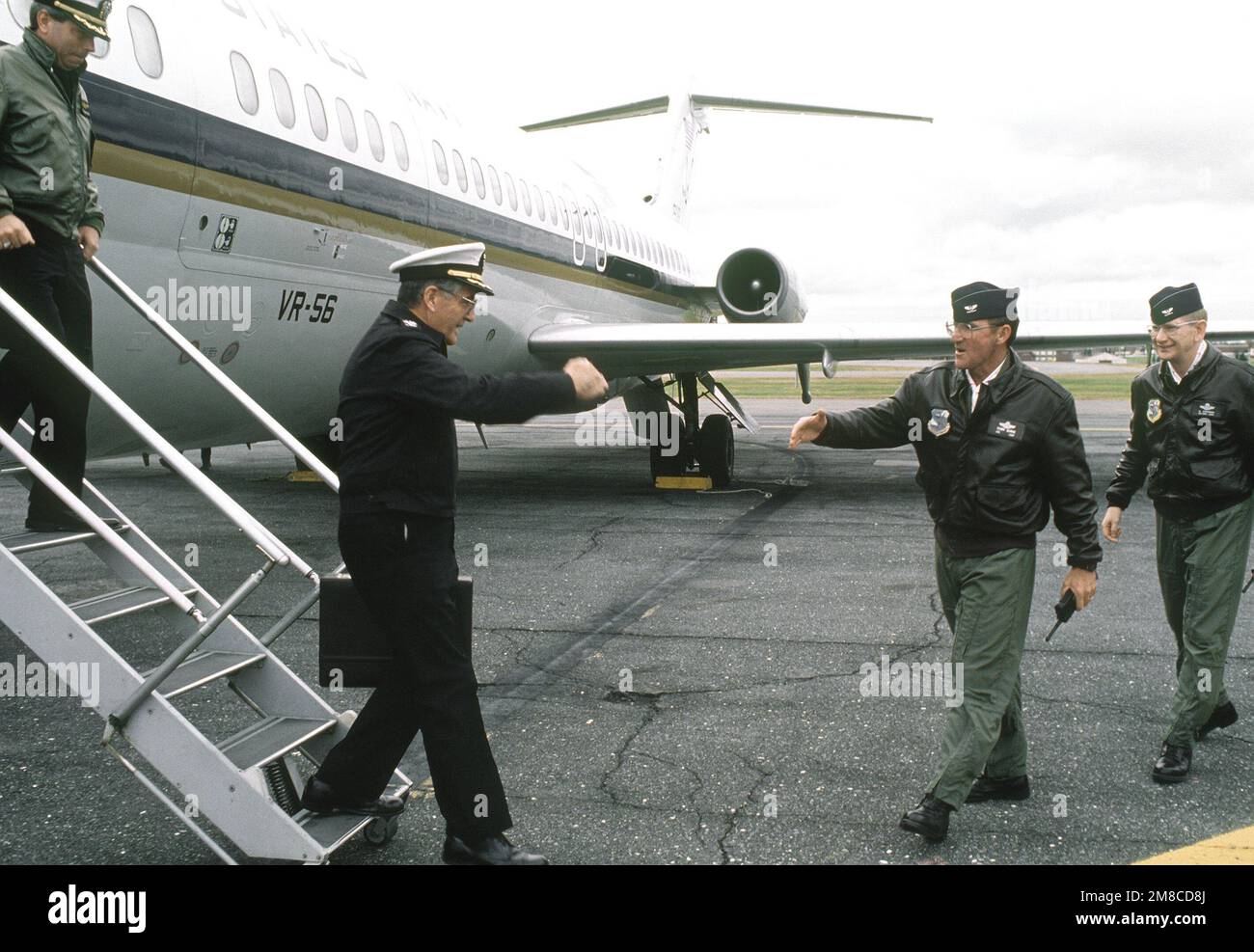 a-navy-captain-is-met-by-two-air-force-colonels-as-he-arrives-at-the