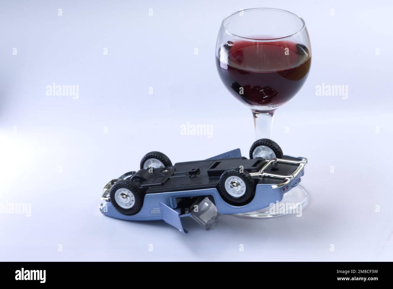 Overturned car on white background and glass with wine, don't drink and drive concept. Stock Photo