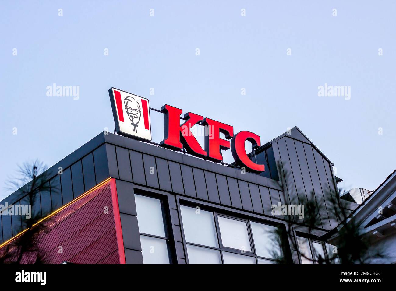 DUSHANBE, TAJIKISTAN - JULY 28, 2022: Red KFC fast food restaurant logo with Colonel Sanders against the blue sky. Stock Photo
