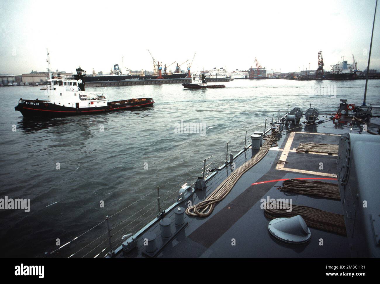 A commercial tug helps maneuver the guided missile destroyer USS ...