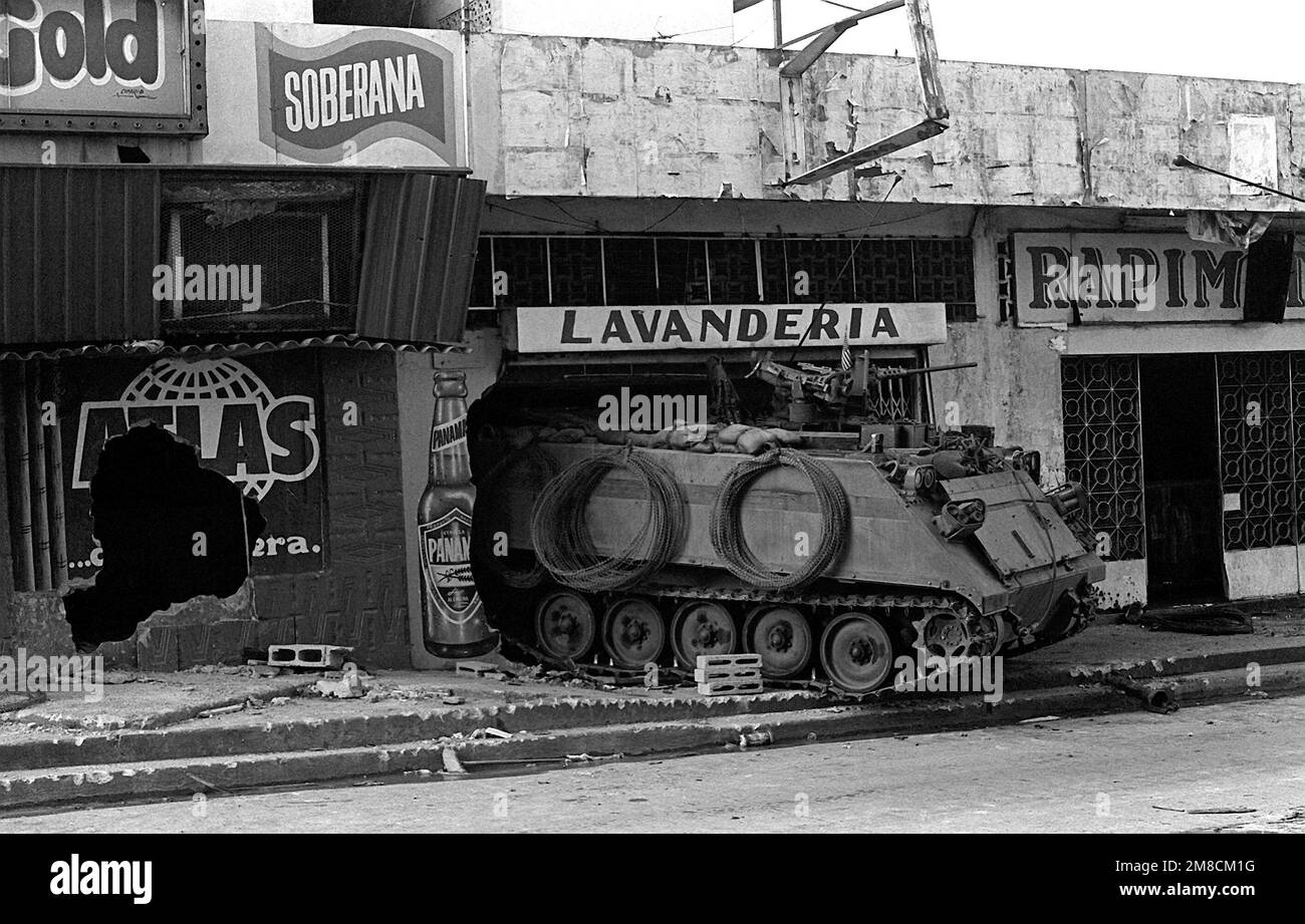 A U.S. Army M-113 armored personnel carrier guards a street near the destroyed Panamanian Defense Force headquarters building during the second day of Operation Just Cause. Subject Operation/Series: JUST CAUSE Base: Panama City Country: Panama (PAN) Stock Photo