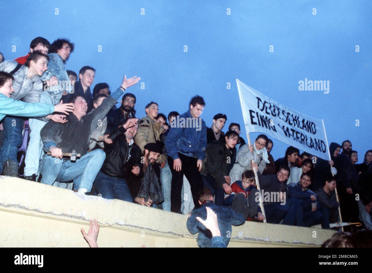 A crowd celebrates atop the Berlin Wall following the official opening ...