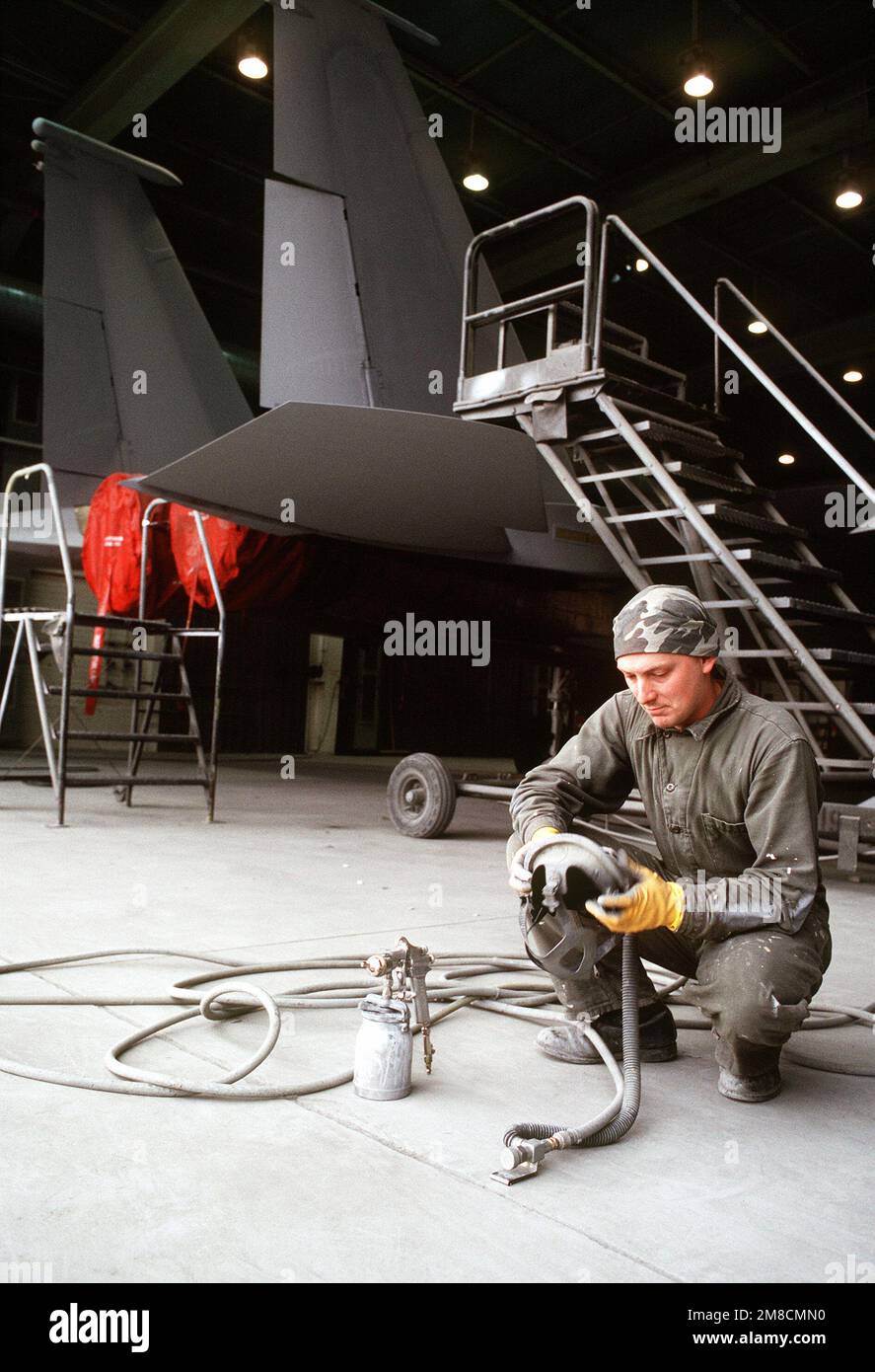 AIRMAN 1ST Class Matthew Sumrell checks a spray gun prior to painting an F-15 Eagle aircraft. The plane is one of 12 to be sold to the Saudi Arabian Air Force for use during Operation Desert Shield. Subject Operation/Series: DESERT SHIELD Base: Bitburg Air Base Country: Deutschland / Germany(DEU) Stock Photo